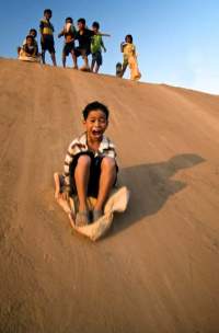 Children slide down a steep cement embankment near a bridge outside Phnom Phen, Cambodia.
