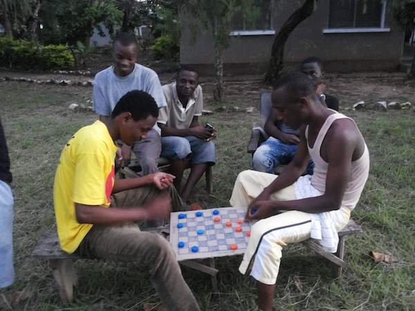 With no power or electronics, these university students play checkers made from a cardboard box and soda bottle lids. (Photo credit: Alyssa MacDonald.)