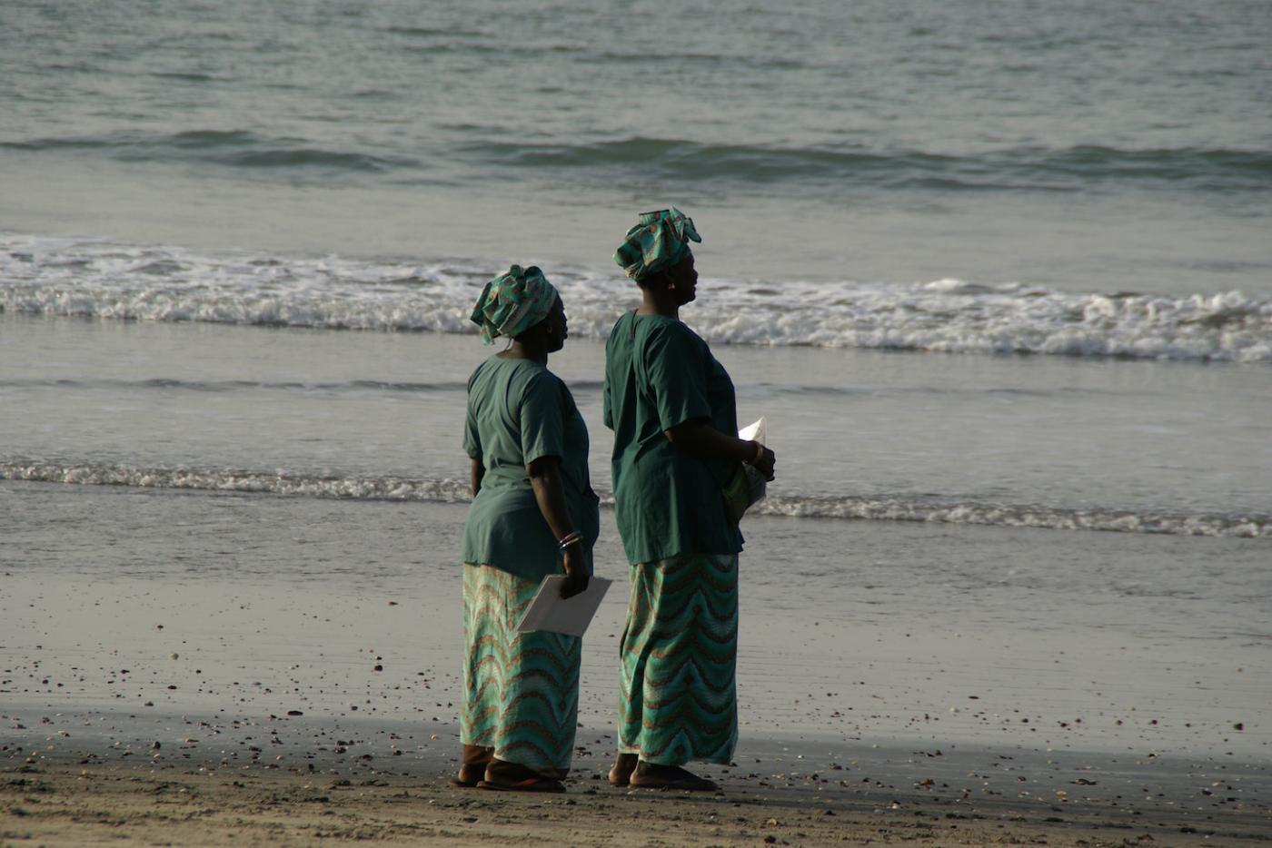 Two women stand on the beach in the Gambia. 