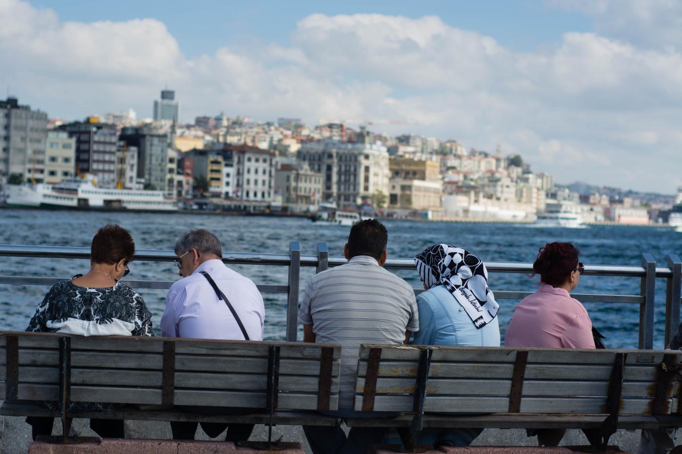 Men and women sit together on a bench in Istanbul, Turkey.