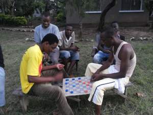 With no power or electronics, these university students play checkers made from a cardboard box and soda bottle lids. (Photo credit: Alyssa MacDonald.)