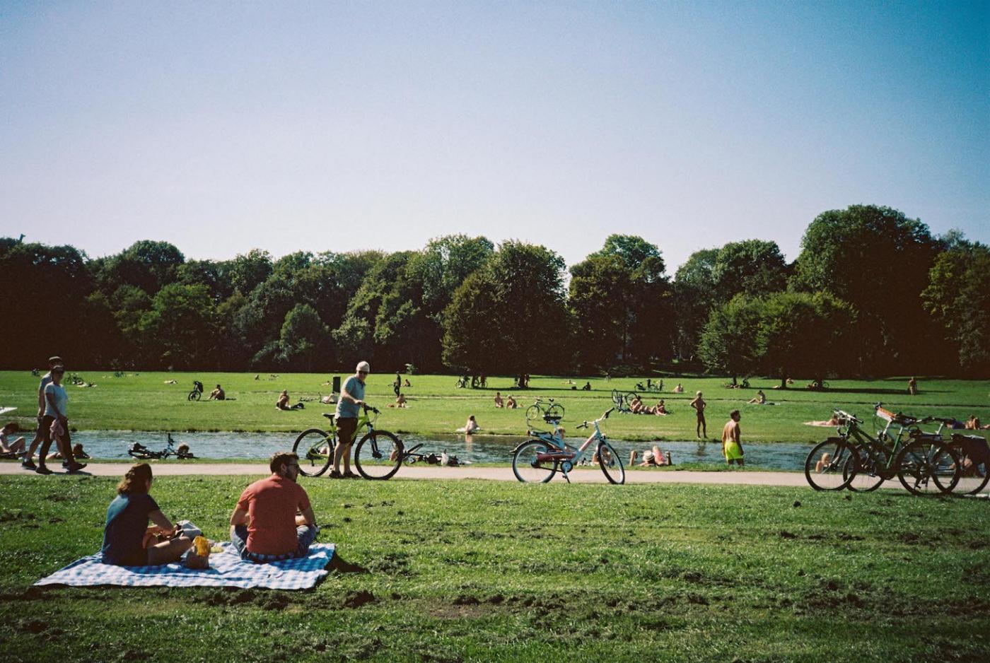 Munich residents relax by a river in the English Garden, Europe&#039;s largest city park.