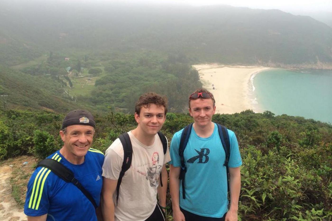 Liam (middle) with, his dad and brother, on a hike with one of Hong Kong&#039;s many beaches in the background. 